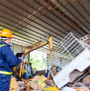 Engineer pointing forward. Engineer driving a loader in the recycling plant.